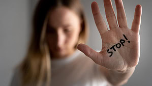 Woman with bruises on her face showing stop sign, palm in focus.